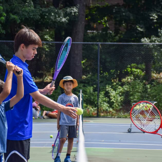 Counselor helping kids at Tennis Camp.